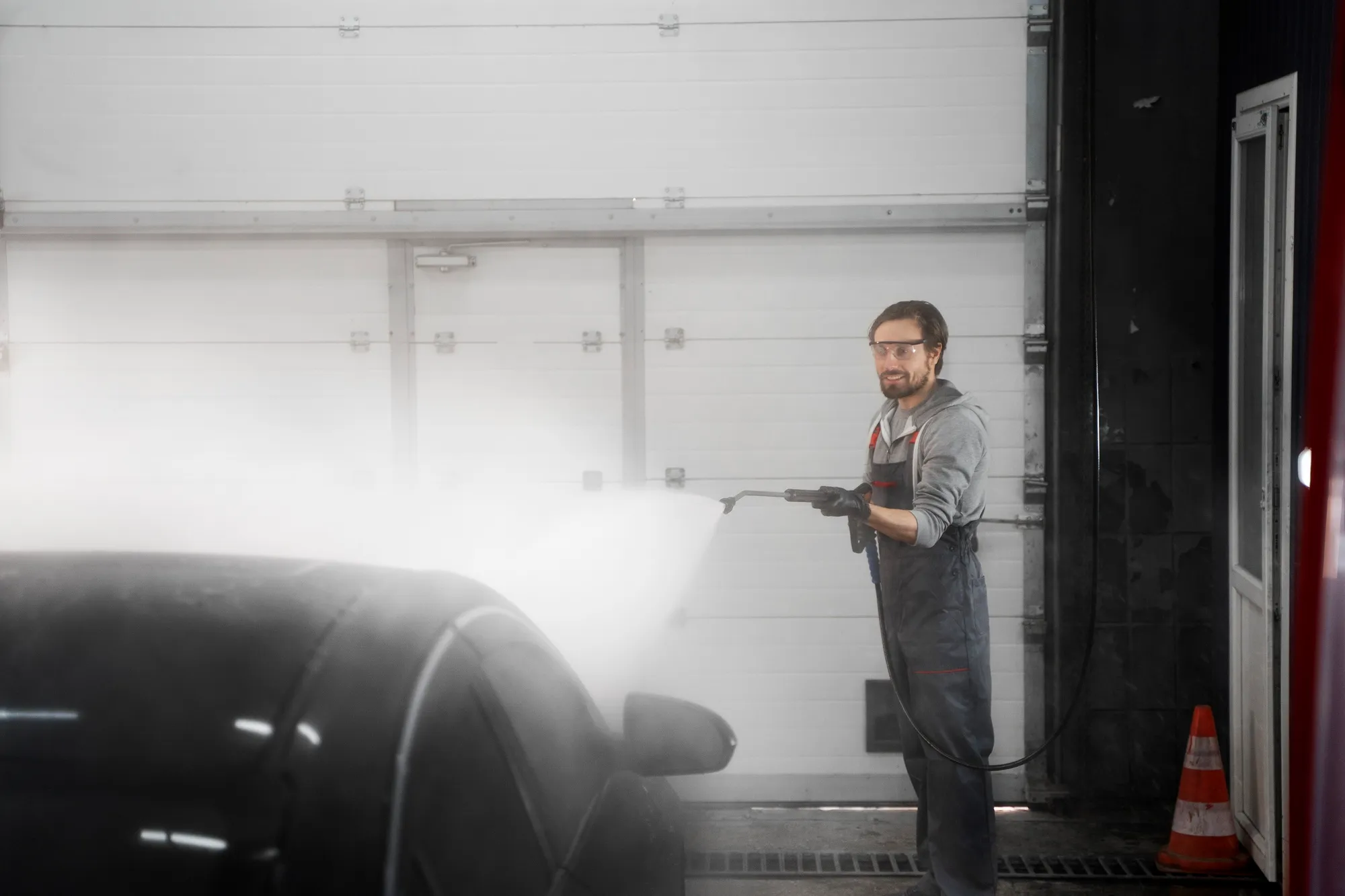 Technicians pressure washing the undercarriage of a truck to prevent corrosion