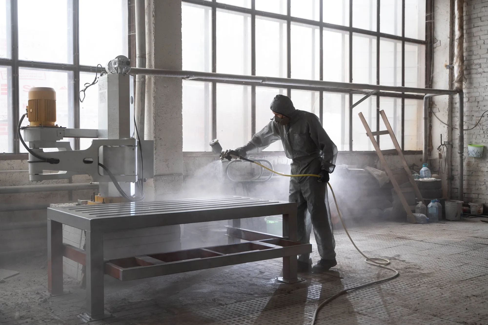 A professional using a pressure washer to clean the floor of an industrial warehouse.