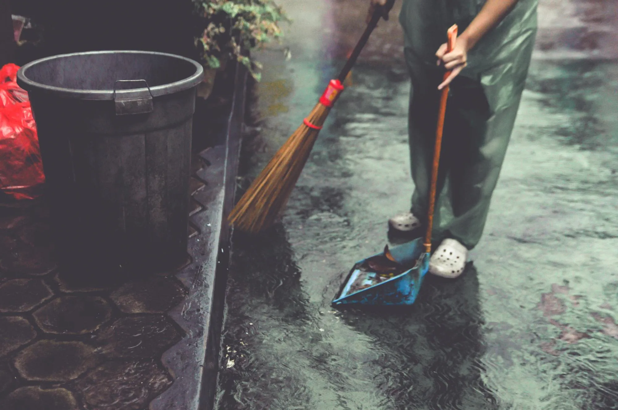 A worker cleaning a catch basin using specialized equipment.