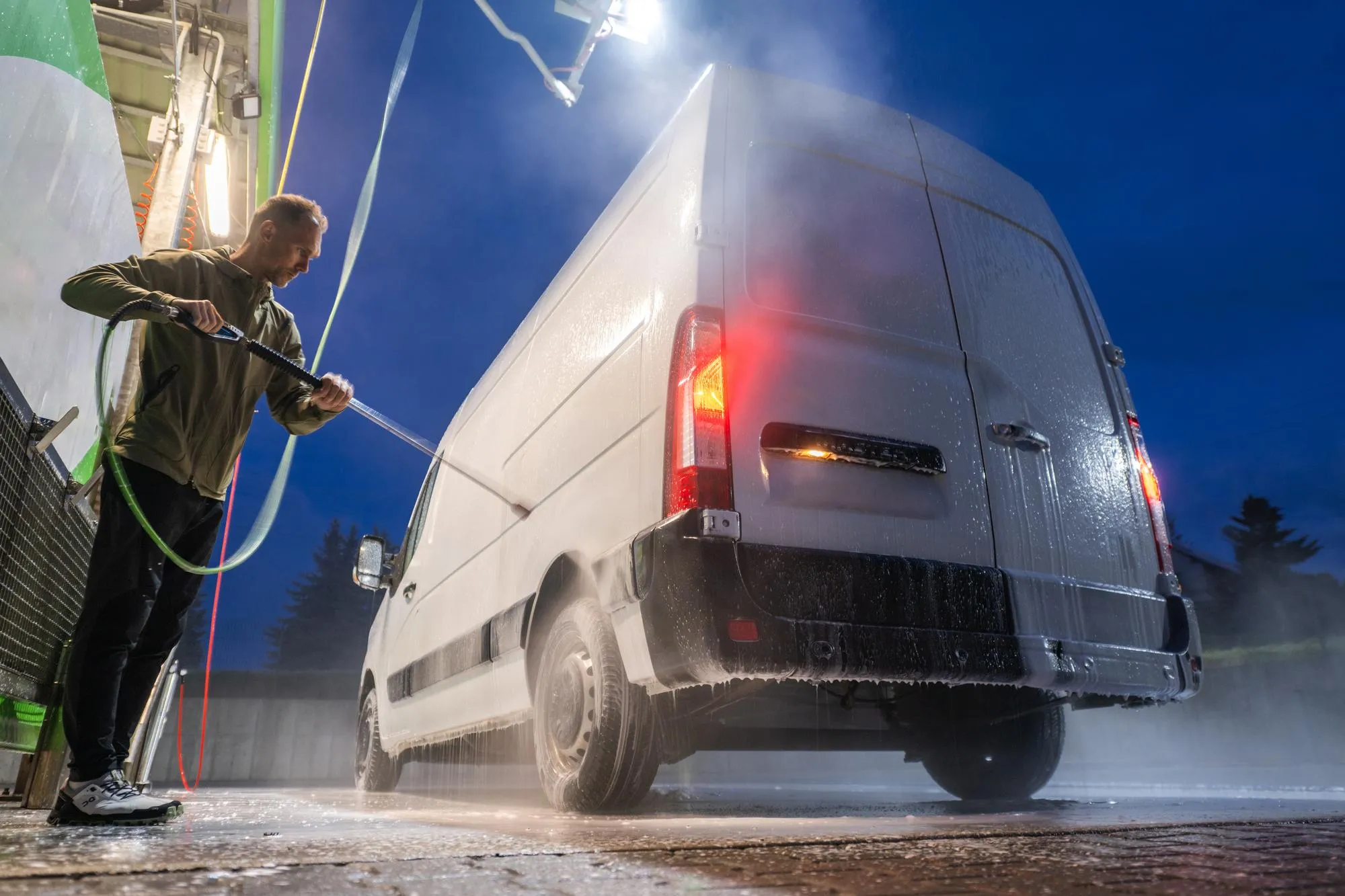 A truck fleet being professionally pressure washed in a lot.