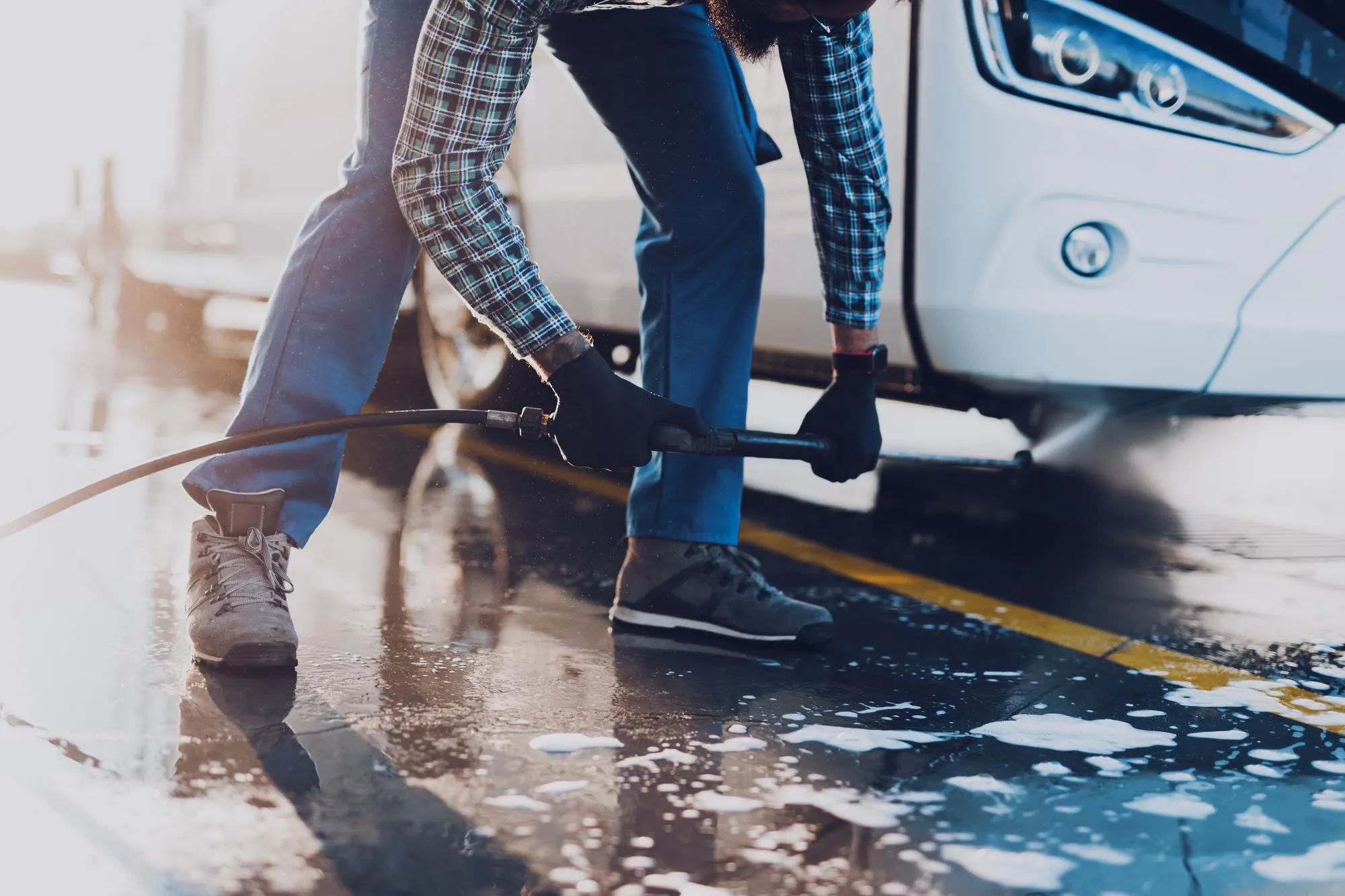 A high-pressure water jet cleaning the undercarriage of a truck.