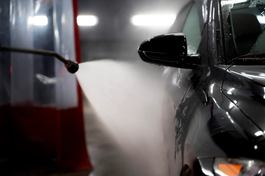 A professional pressure washing an underground parkade with equipment.