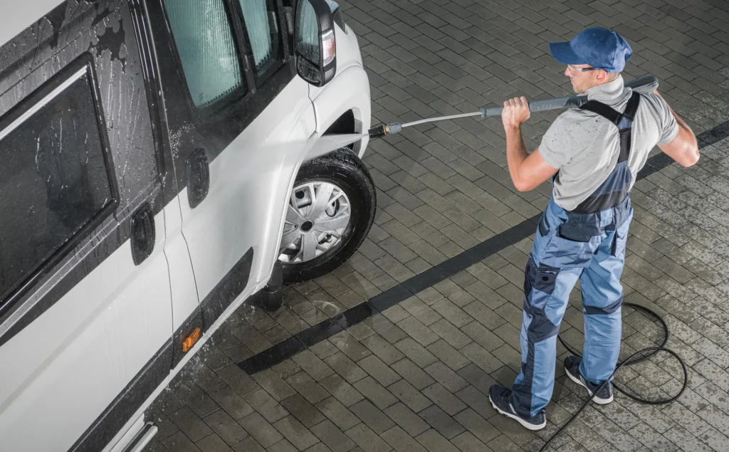 A professional worker pressure washing a large fleet truck.